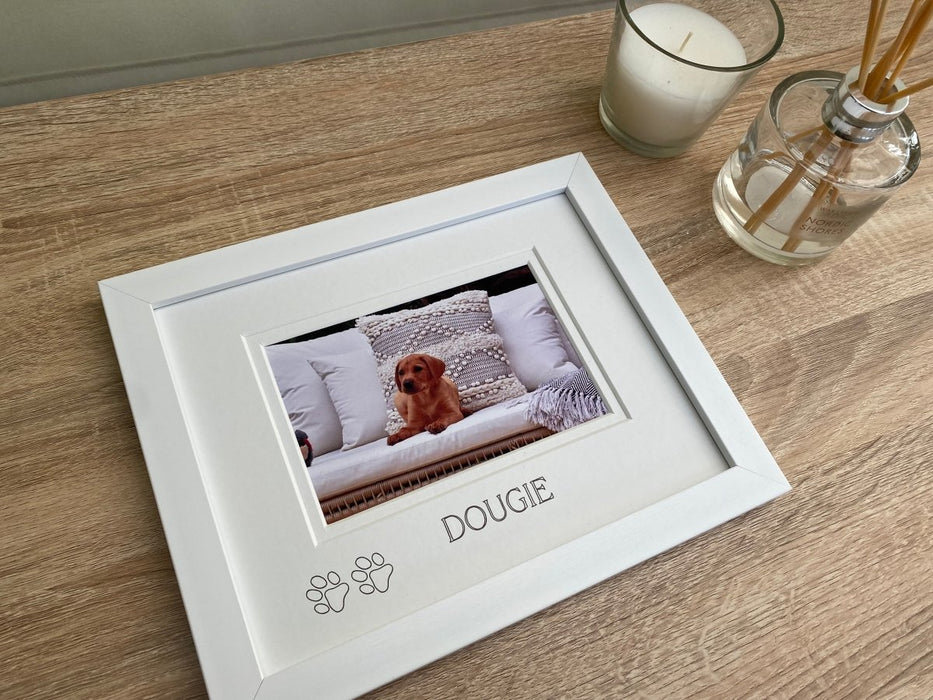 Contemporay white frame, a picture of a fox red lab sitting on the sofa. Next to a white candle and diffuser for home decor.