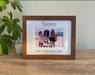 A photo of the sisters inside a brown picture frame with the personalisation, Sisters is inscribed on the top, next to a candle..