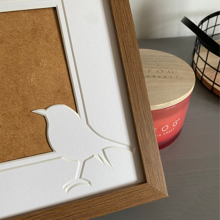 Small robin shaped mount in a picture frame on dresser