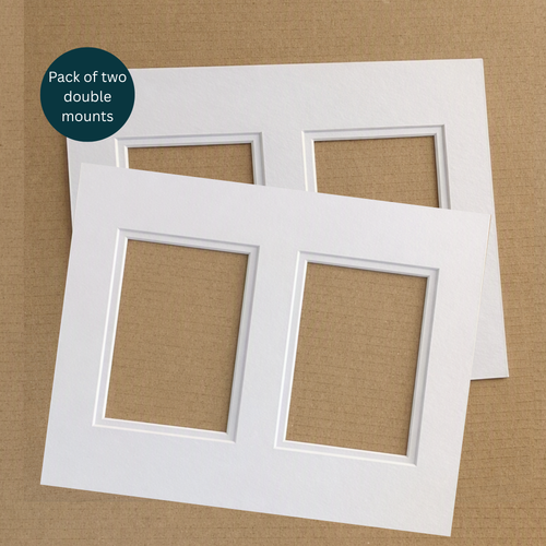 Two white double-mount photo mats stacked on a brown kraft paper background, with a dark teal circular badge in the top-left that reads 'Pack of two double mounts'.