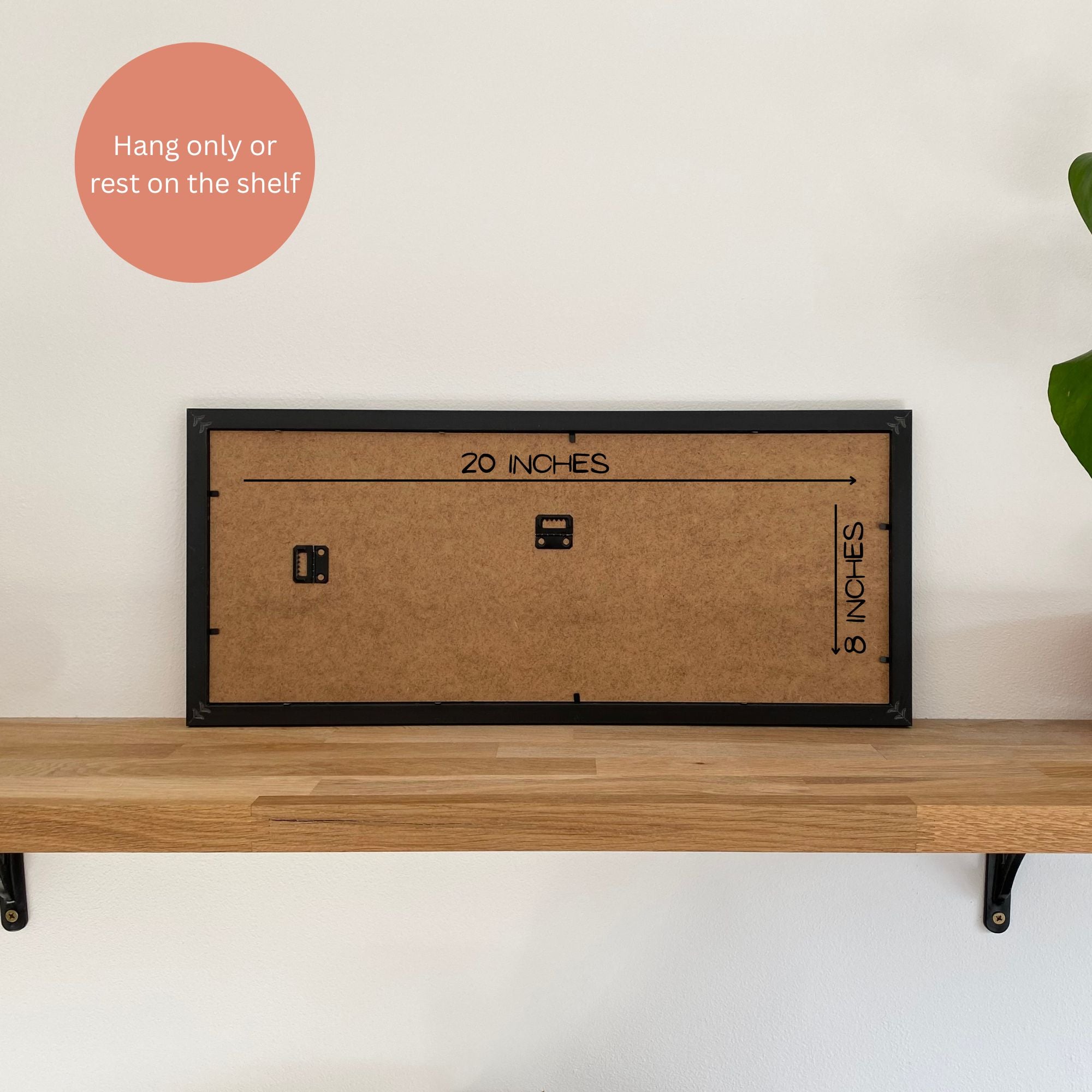 Back of black frame with dimensions on wooden shelf against a light wall