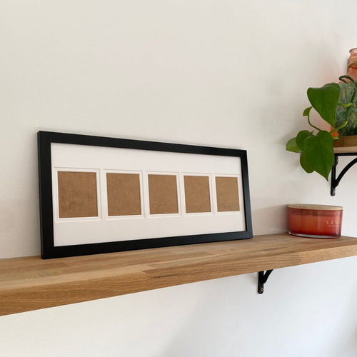 Black 5-aperture picture frame displaying family photos on wooden shelf