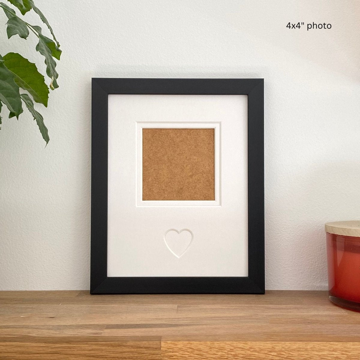 Black framed photo display with cork board insert on a wooden surface.