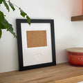 Black single-aperture heart picture frame displaying family photo on wooden shelf