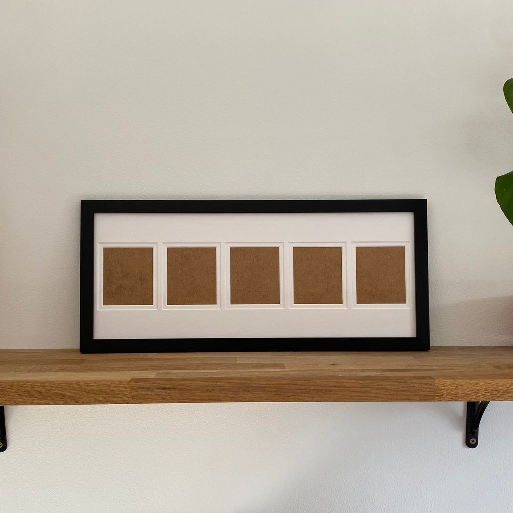 Framed artwork with five apertures on a wooden shelf against a white wall.