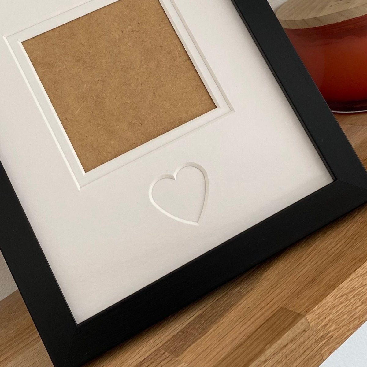 Framed picture with a heart cutout on a wooden surface