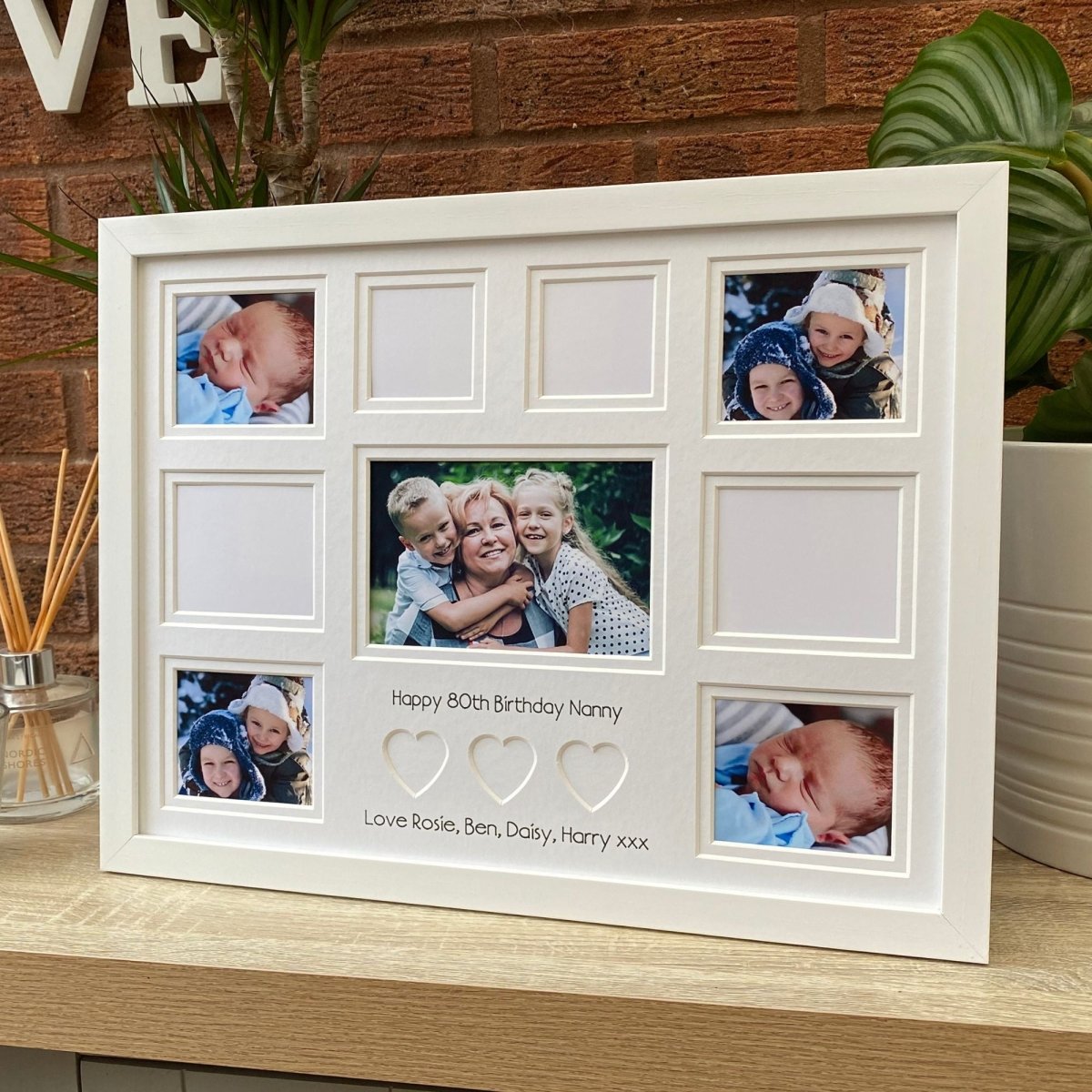 Large picture frame with white mounted, heart-shaped and apertures on tabletop next to a diffuser