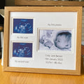 Light brown wood-grain effect photo frame with ultrasound images and baby landscape photo on a wooden surface