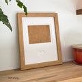 Light brown single-aperture heart picture frame displaying lifetime memories on wooden shelf