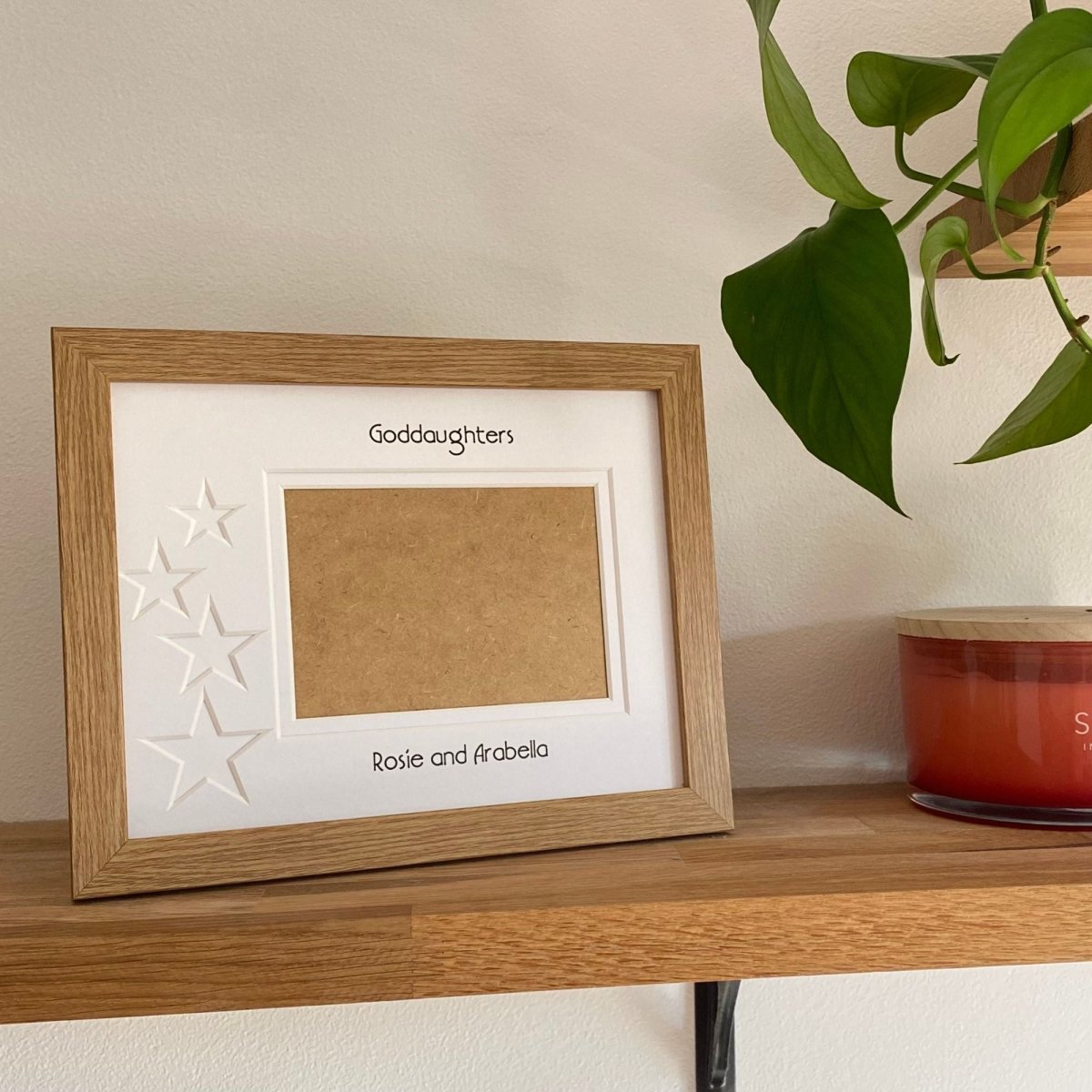 Light brown 1-aperture star frame displaying a family photo on wooden shelf