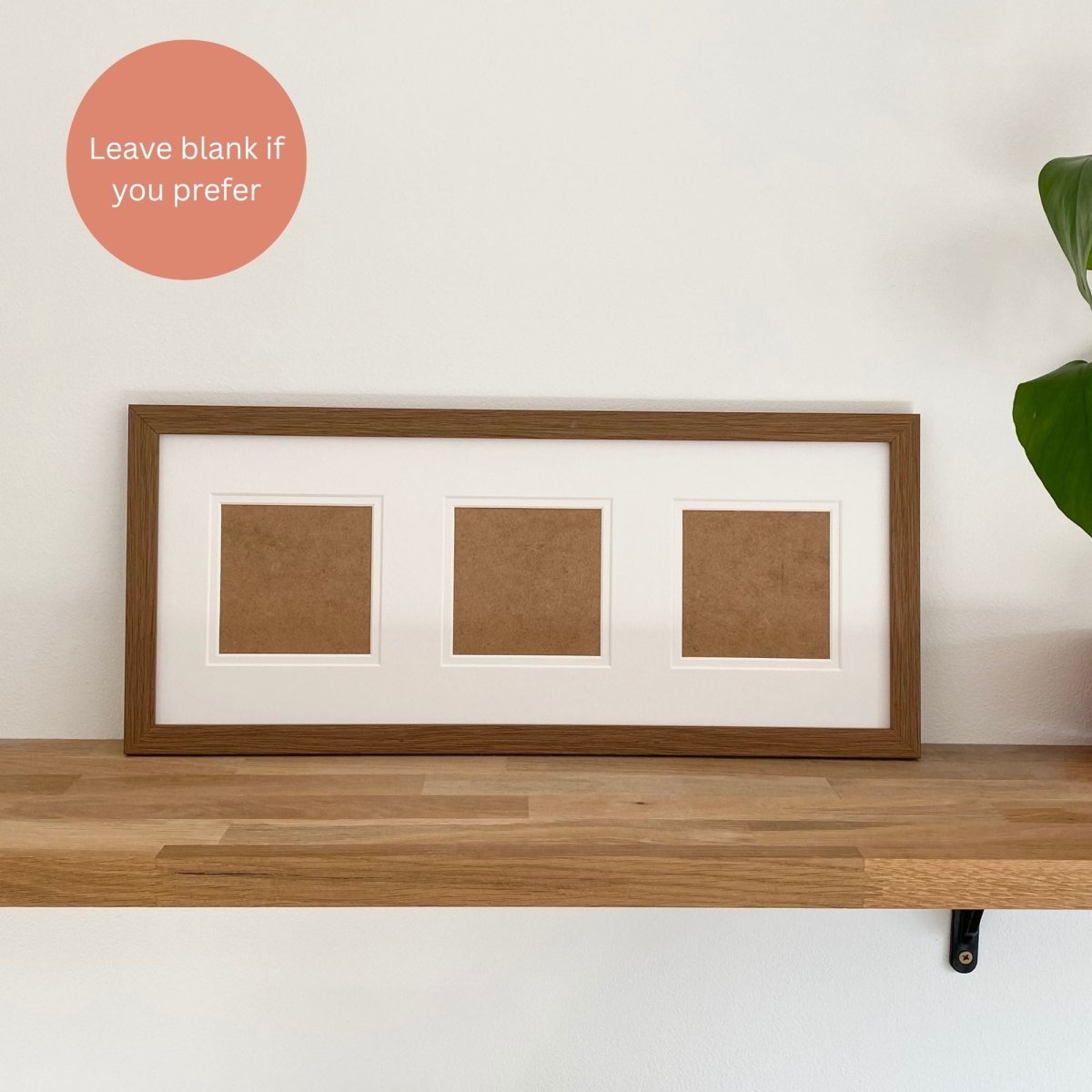 Wood-grain effect frame with three brown square panels on a wooden shelf against a white wall.
