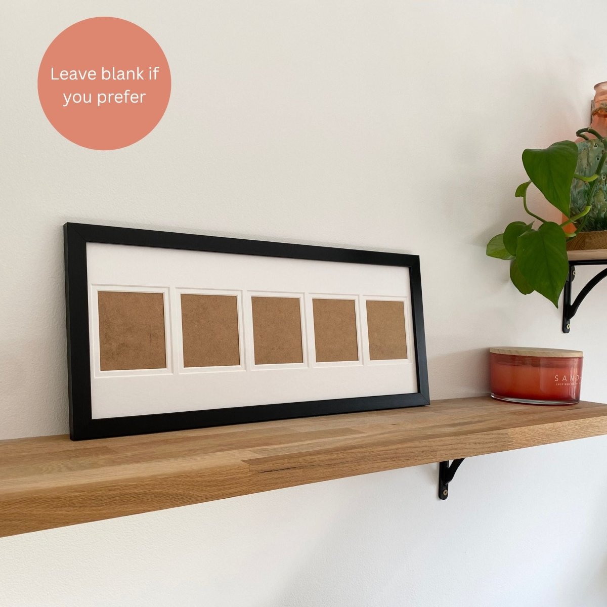 Black five aperture frame on wooden shelf, white background with red candle and gree leaf