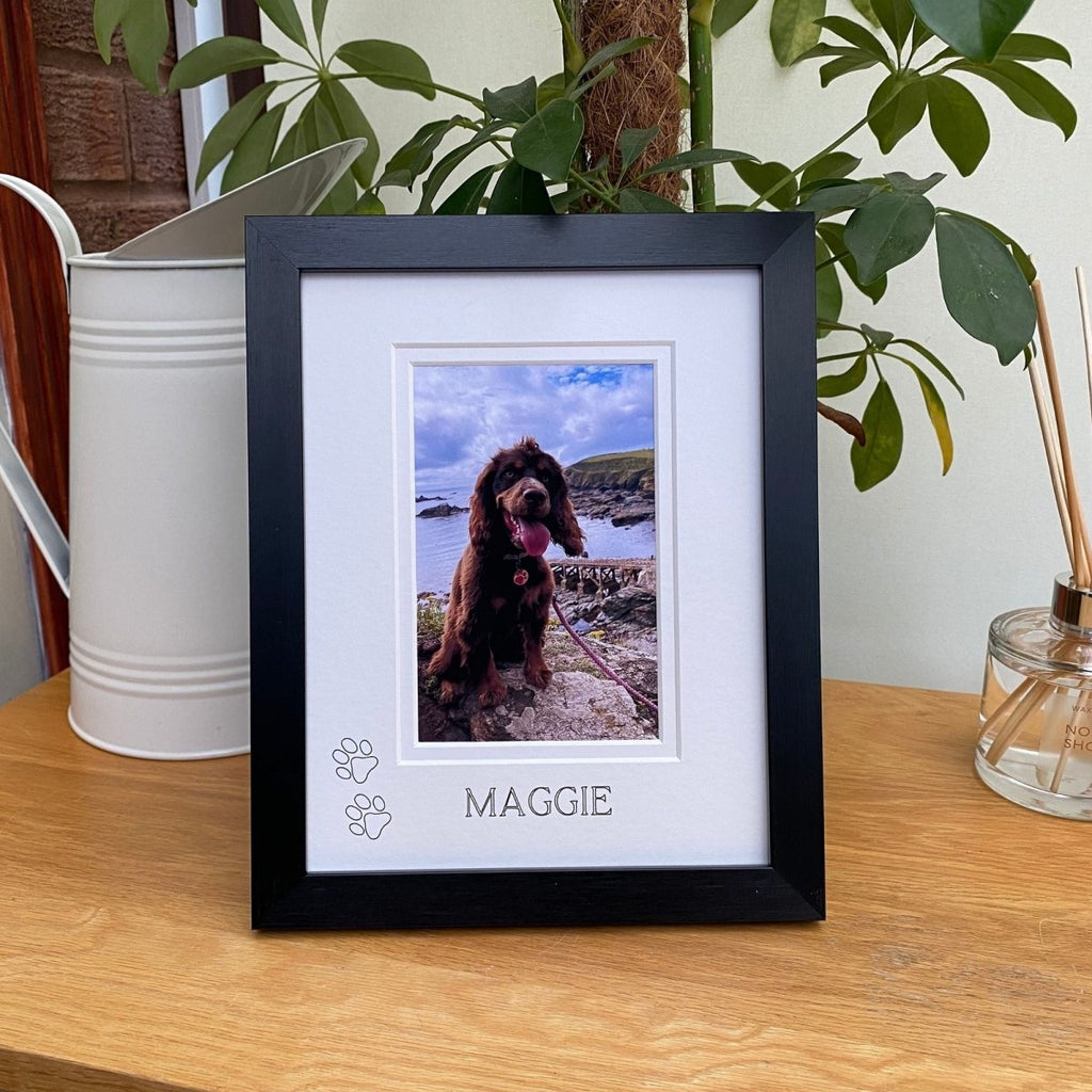 Framed photo of a dog named Maggie on a wooden surface with plants in the background