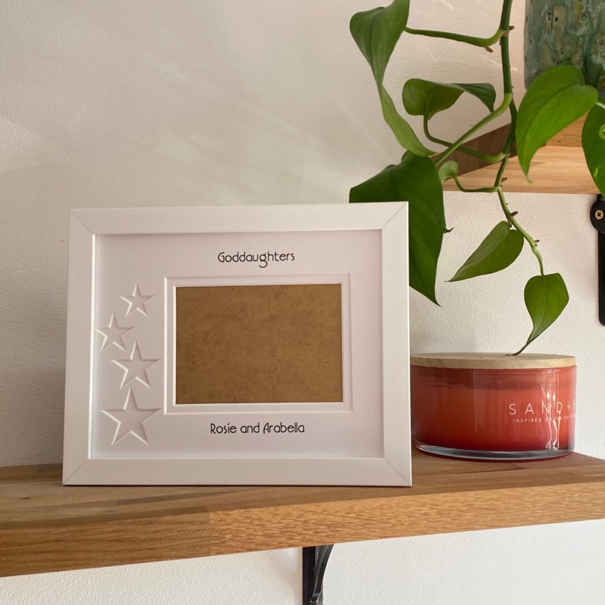 White 1-aperture star frame displaying a family photo on wooden shelf