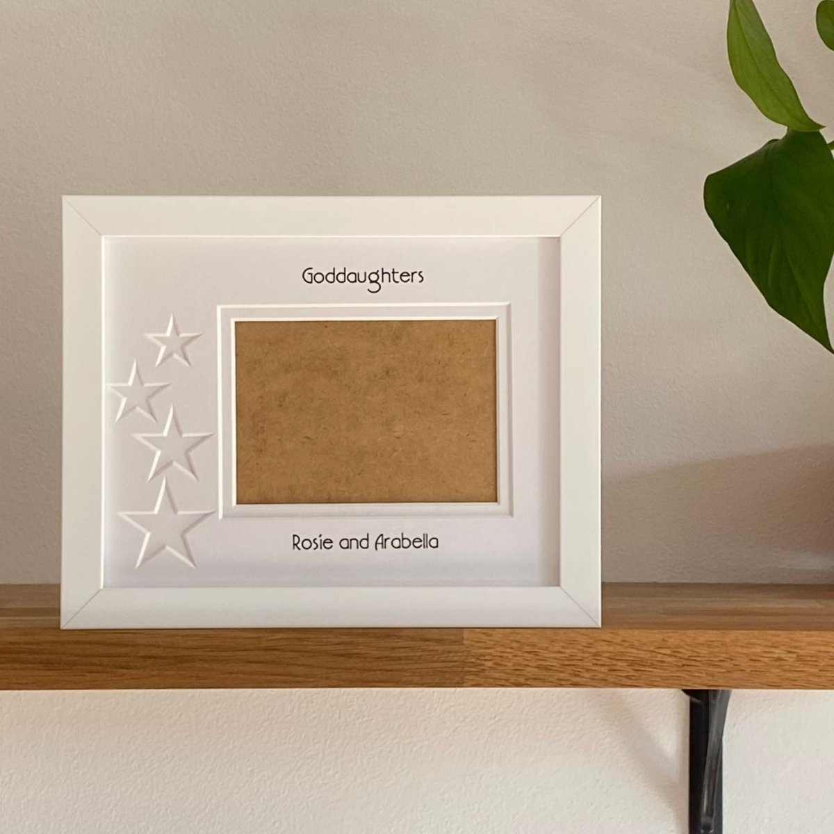 White single aperture photo frame with star designs on wooden surface