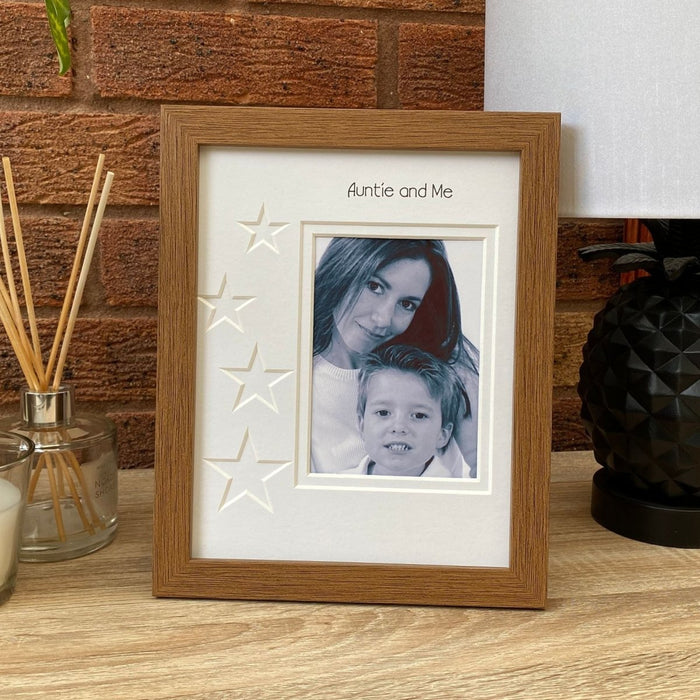 Dark brown picture frame of an Auntie and nephew, freestanding on the tabletop next to a white lamp and a diffuser