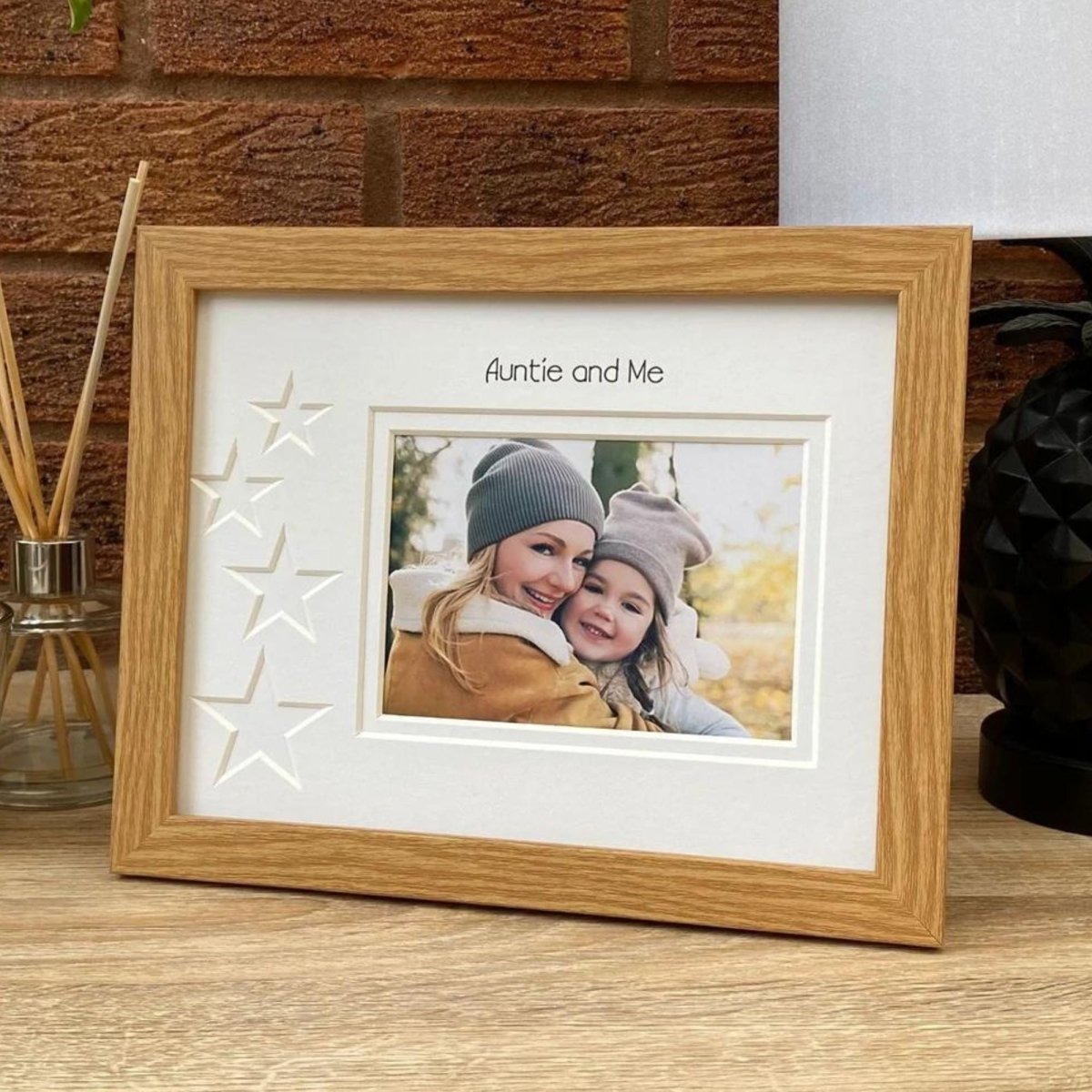 Brown picture frame on a tabletop next to a lamp and diffuser