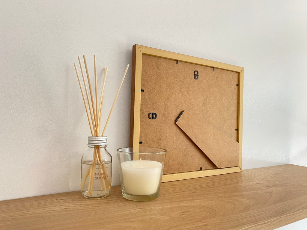 Freestanding Dark brown picture frame on shelf next to a white candle and diffuser