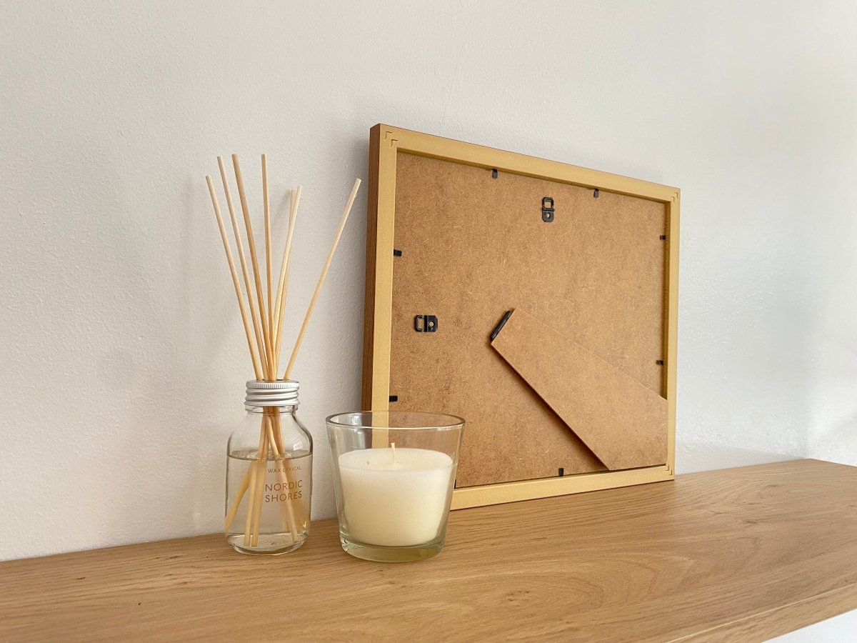 Freestanding Dark brown picture frame on shelf next to a white candle and diffuser