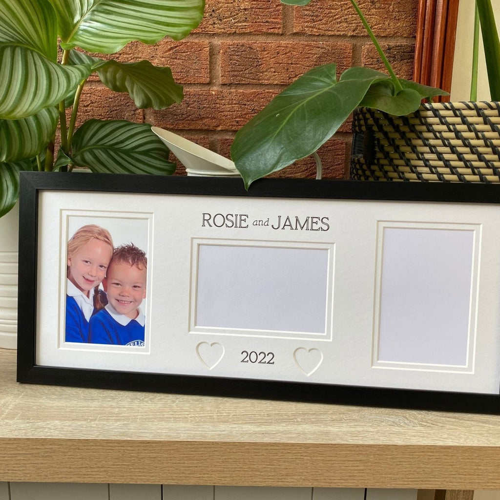 Black, 3x picture school frame on tabletop next to a green plants