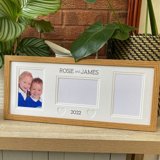 Light brown, wood-grain effect multipicture School frame on tabletop next to green plants