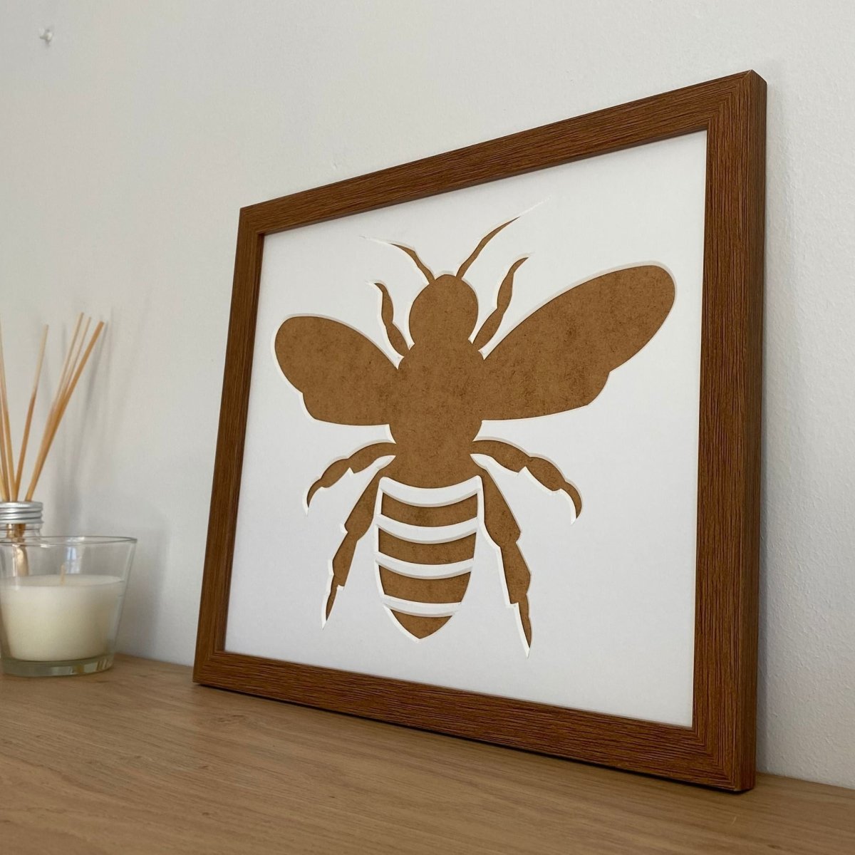 Dark brown picture frame, Bee silhouette on the shelf next to a white candle
