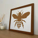 Dark brown picture frame, Bee silhouette on the shelf next to a white candle