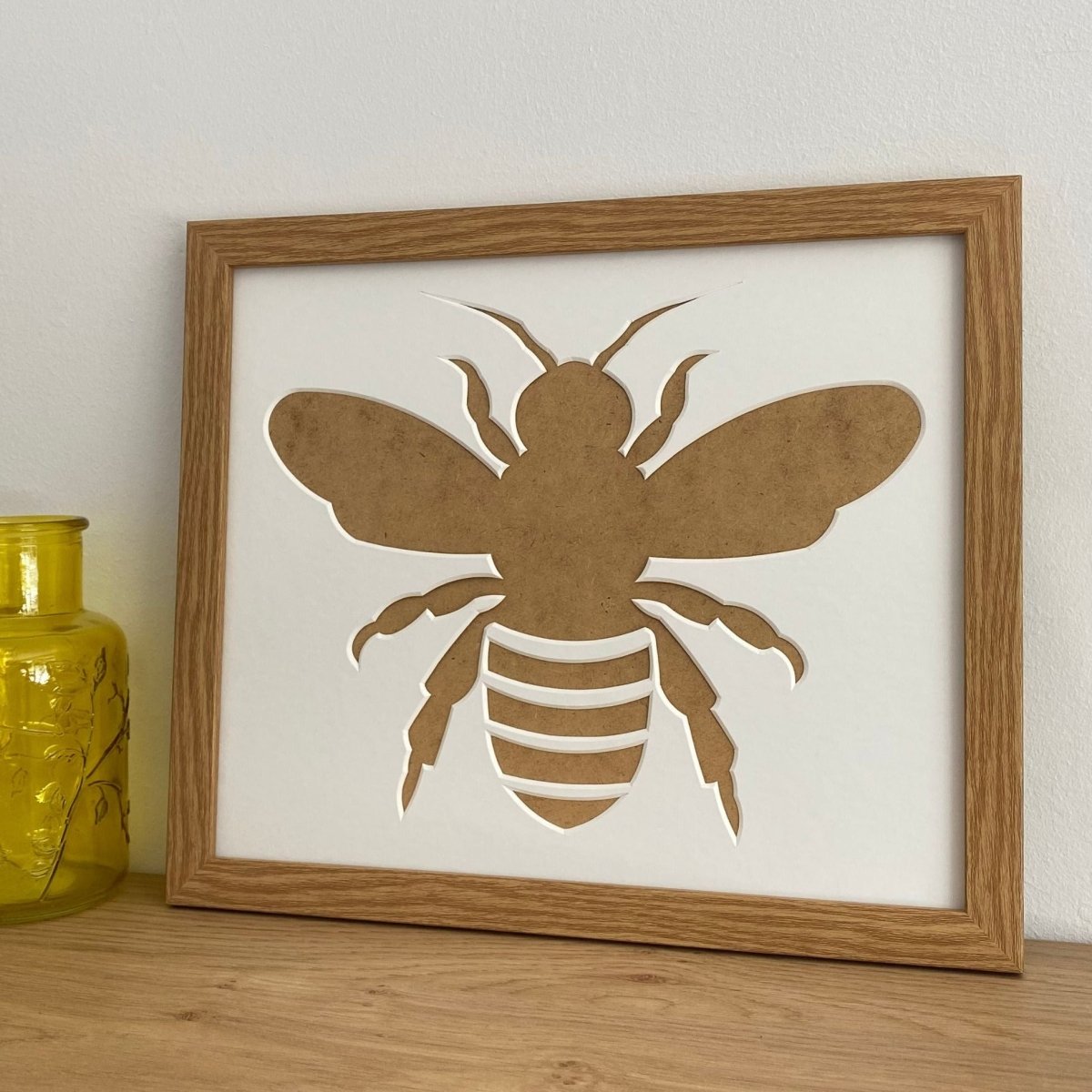 silhouette brown picture frame on the shelf next to a yellow glass pot