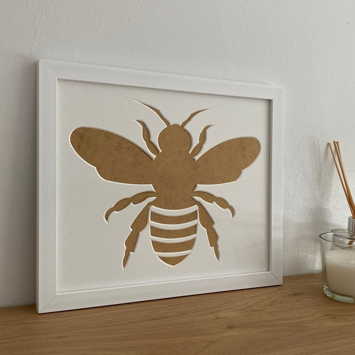 Bee Silhouette white frame on the shelf next to a candle