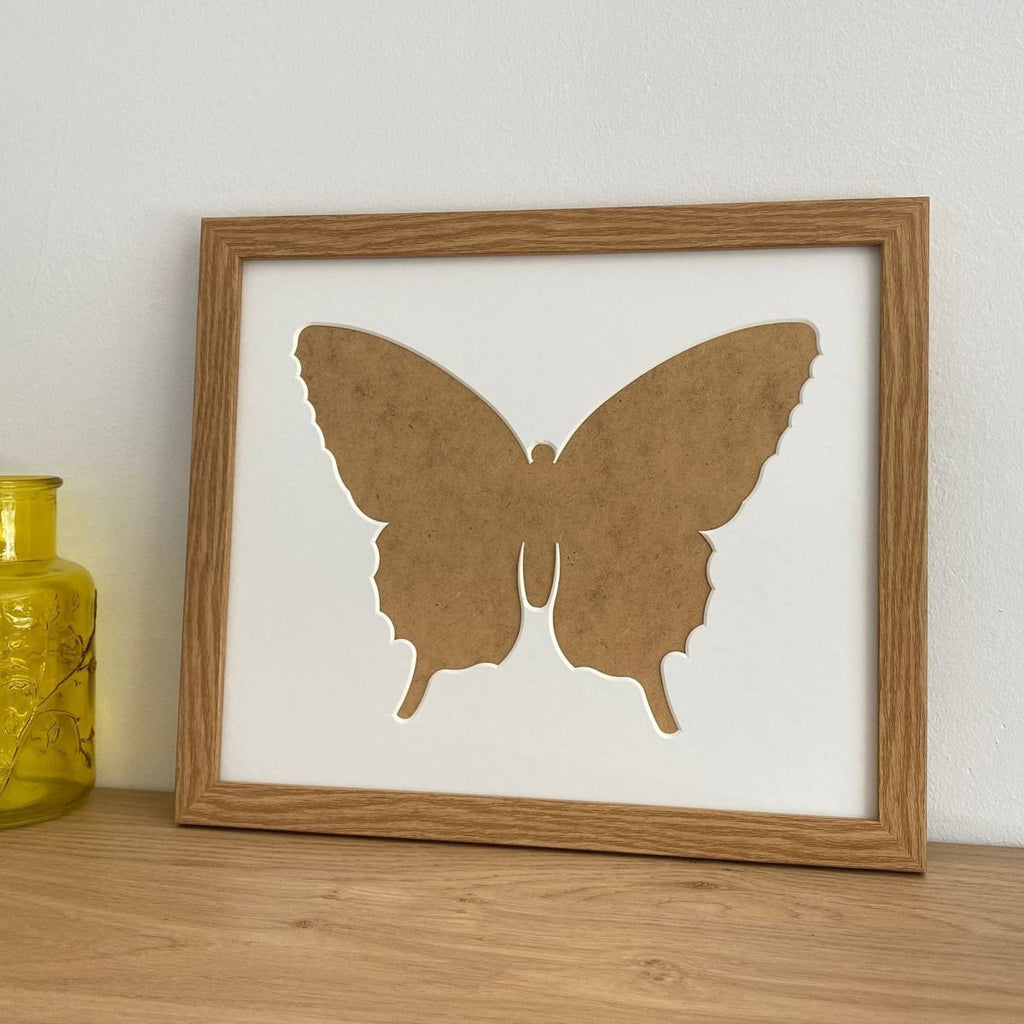 Light brown Butterfly silhouette picture frame next to a yellow glass pot on the shelf