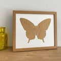 Light brown Butterfly silhouette picture frame next to a yellow glass pot on the shelf