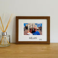 A brown Holiday Picture Frame, displaying a landscape photograph of a couple with the text saying Milan and a year.