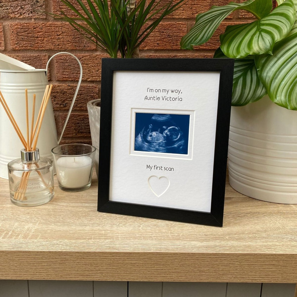 Black frame for Auntie to be, on tabletop next to a white candle, jug and green plant