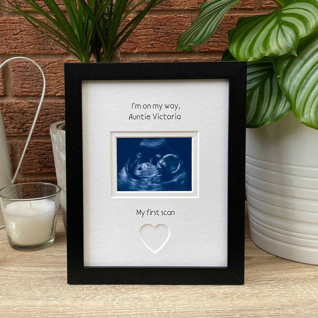 Black frame for Auntie to be, on tabletop next to a white candle and green plant