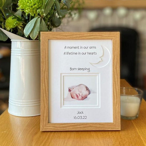 Moon, Born sleeping Picture frame on table nect to a jug of flowers and a candle