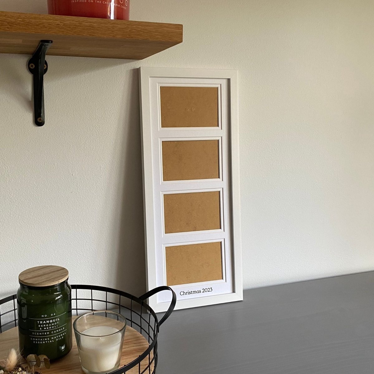 Multi Landscape Aperture Frame 4 Photos, White - holds four landscape photos on grey tabletop next to black mesh tray and shelf with candles - Azana Photo Frames