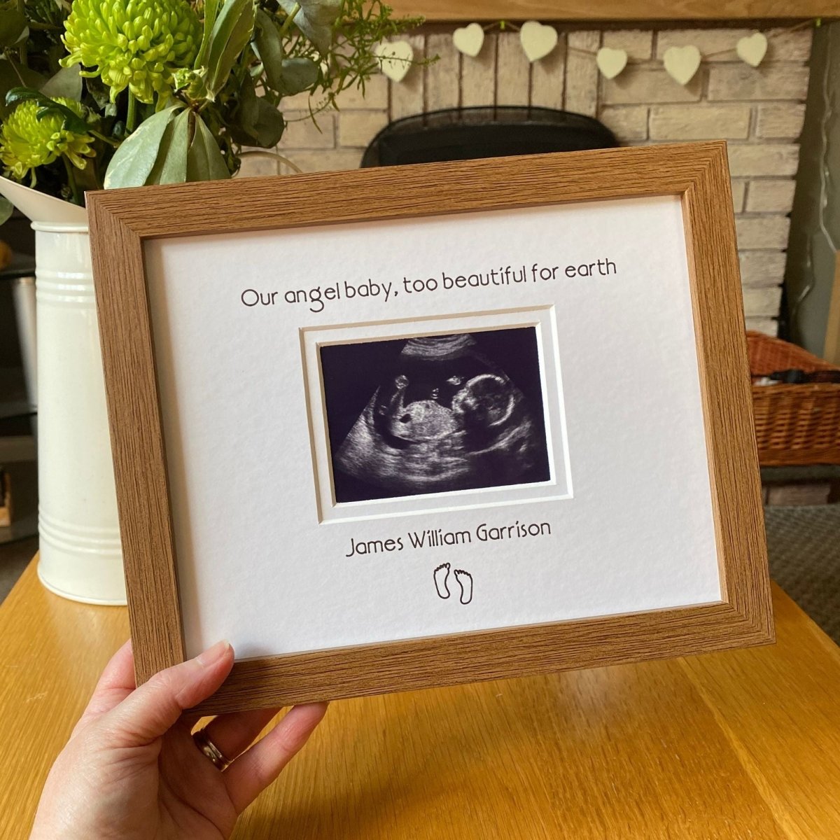 Holding a dark brown, wood-grain effect frame, angel baby too beautiful for earth for baby loss, memorial