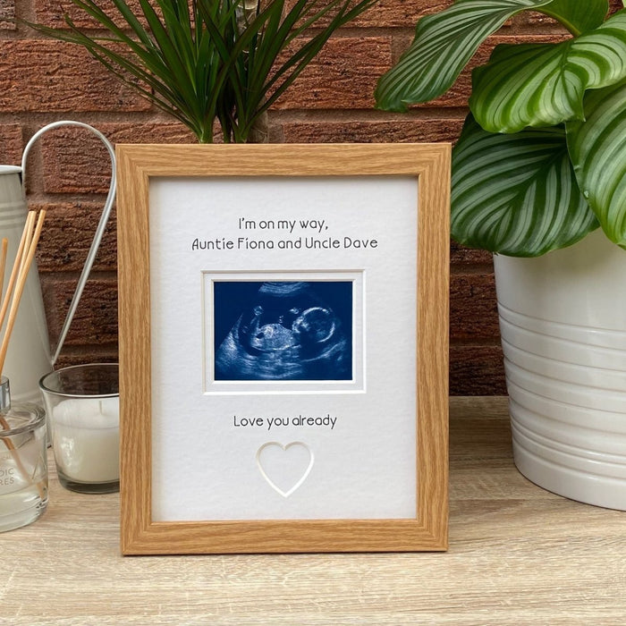 First scan picture frame on the tabletop, next to a candle, diffuser, jug and greenery plants