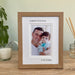 Light brown, Wood-effect Portrait Picture Frame of a Girls 1st love is her Daddy, resting on the tabletop surrounded by a white candle and diffuser