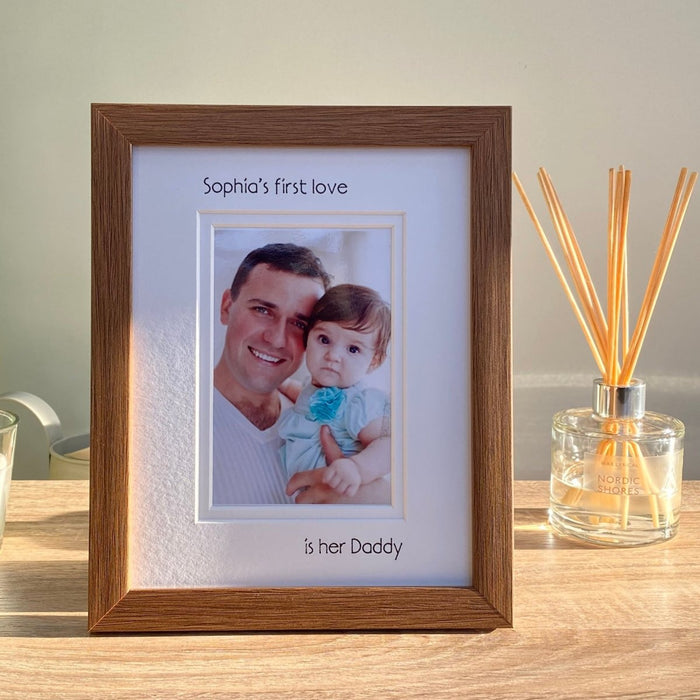 Dark brown Girl's 1st love is her Daddy Picture Frame, resting on the tabletop surrounded by a white candle, diffuser and plant