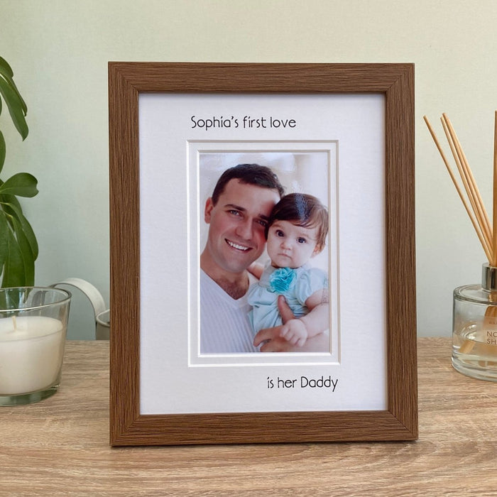 Dark brown Daughter 1st love is her Daddy Picture Frame, resting on the tabletop surrounded by a white candle and diffuser