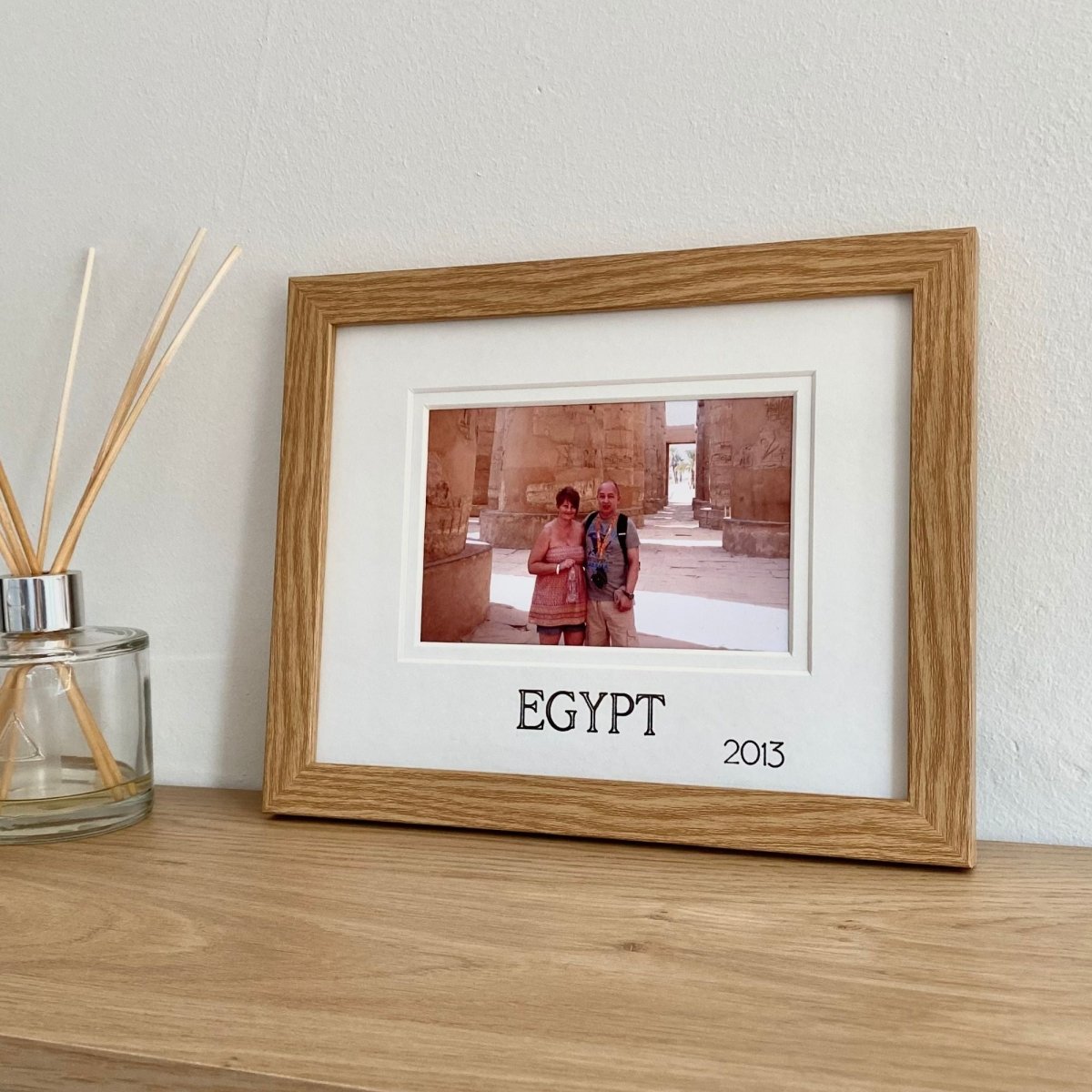 Landscape holiday picture frame on a shelf next to a candle