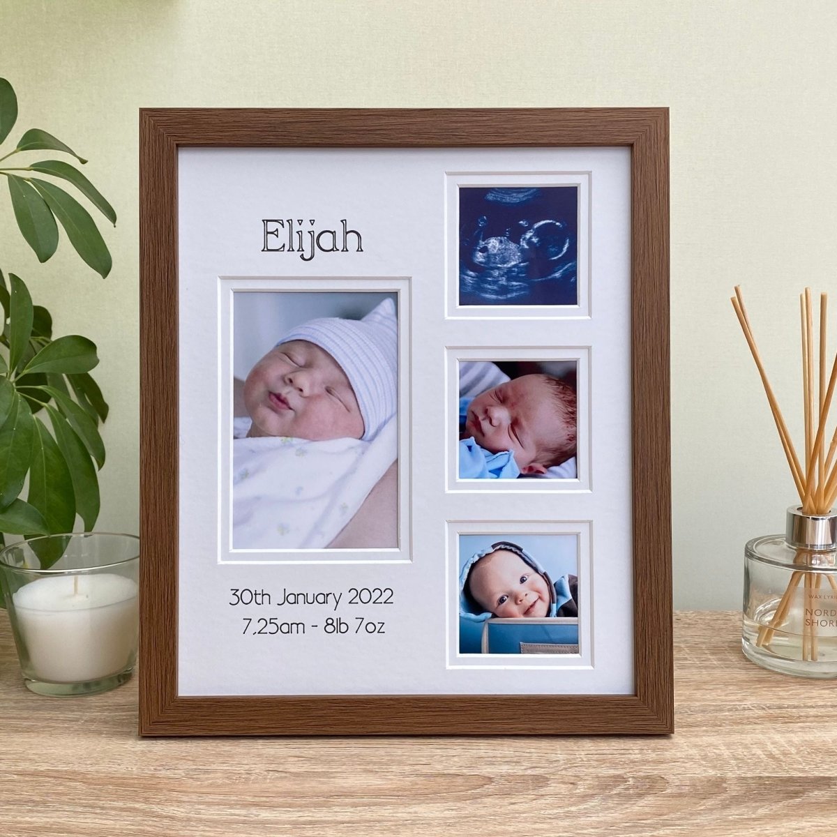 Dark brown, wood-effect multipicture collage frame freestanding next to a white candle, diffuser and plant