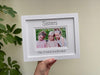 Holding up the white 'Sisters' picture frame in front of the green plant against the cream blinds. An image of all the girls as sisters