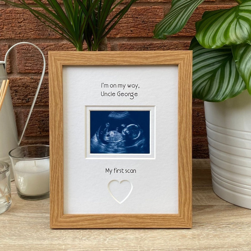 Light brown picture frame on tabletop next to a plant and candle