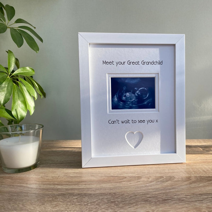Freestanding, contemporary white picture frame, scan image of your Great Grandchild with a heart shape. Next to a white candle and green plant