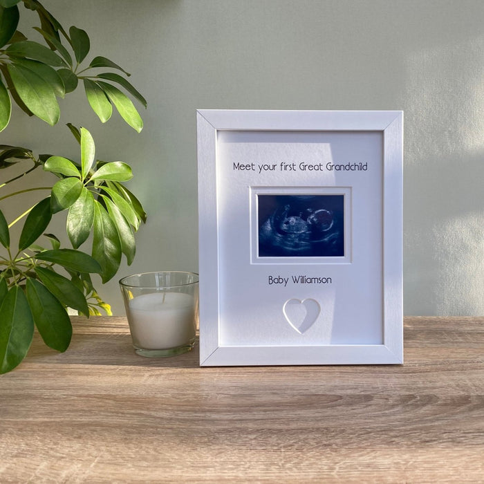 Contemporary white frame, sonogram image of your 1st Great Grandchild with a heart shape. Next to a white candle and green plant