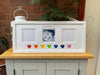 Rainbow hearts personalised picture frame on the tabletop next to a plant and outdoors candle