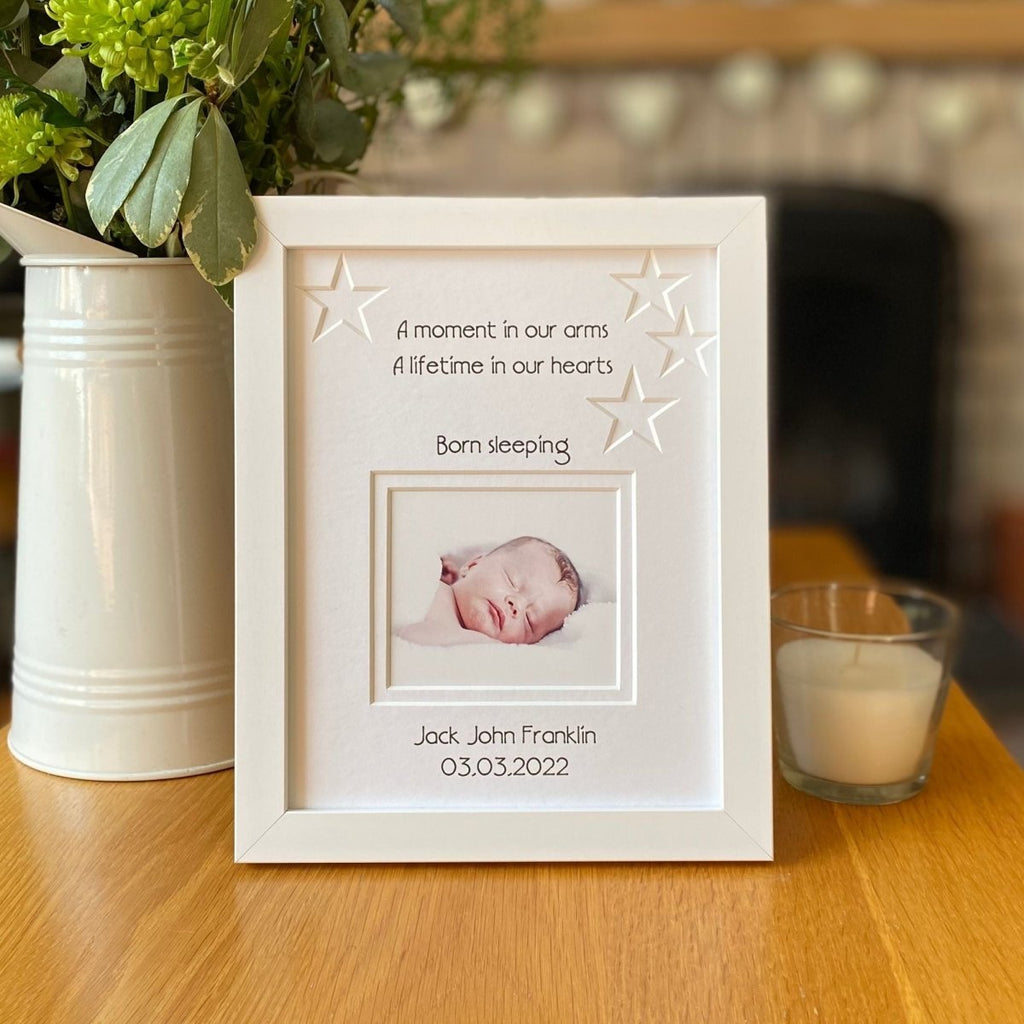 Born sleeping white contemporary picture frame on table, next to a jug of flowers