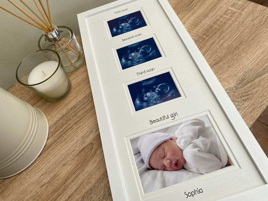 White collage baby scan picture frame laying on tabletop next to a white candle, diffuser and a jug